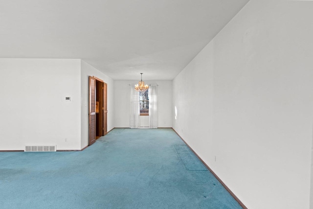 carpeted spare room featuring an inviting chandelier