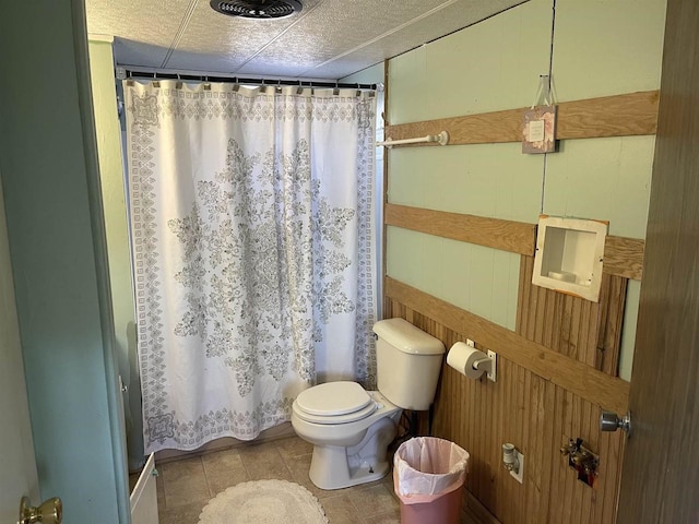 bathroom featuring toilet, tile patterned flooring, a textured ceiling, and a shower with curtain