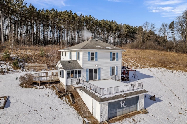 snow covered back of property with a wooden deck