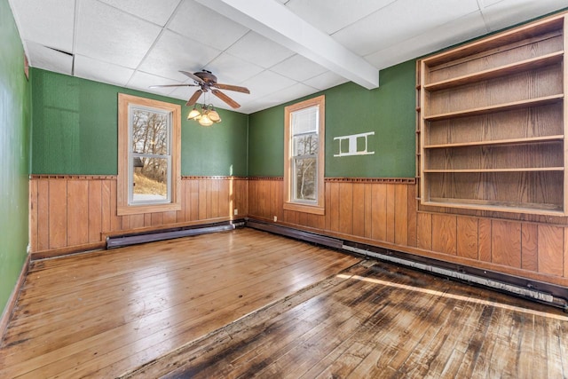 spare room with hardwood / wood-style floors, beam ceiling, and a wealth of natural light