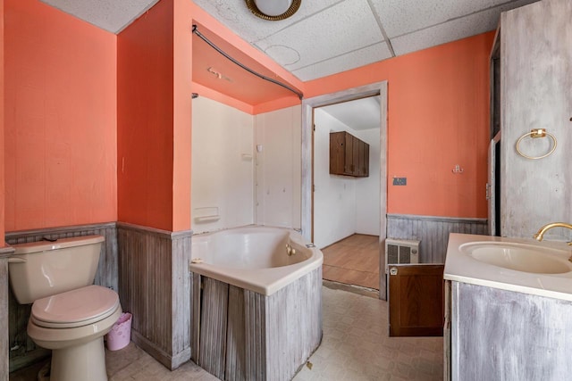 bathroom with vanity, a washtub, toilet, and a drop ceiling