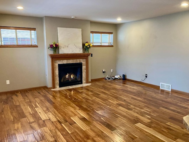 unfurnished living room featuring hardwood / wood-style floors and a tile fireplace