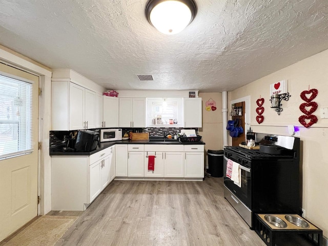 kitchen featuring a textured ceiling, white cabinetry, sink, stainless steel range with gas cooktop, and light hardwood / wood-style flooring