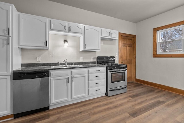 kitchen with dark wood-type flooring, appliances with stainless steel finishes, sink, and white cabinets