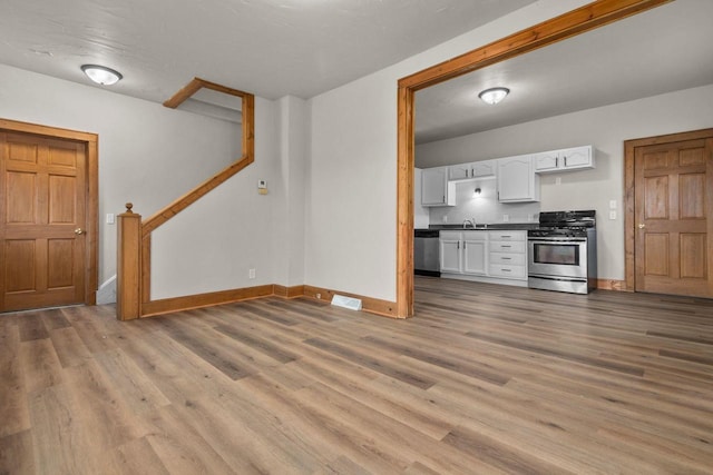 kitchen featuring hardwood / wood-style flooring, white cabinetry, appliances with stainless steel finishes, and sink