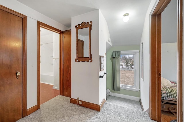 hall featuring vaulted ceiling and light colored carpet