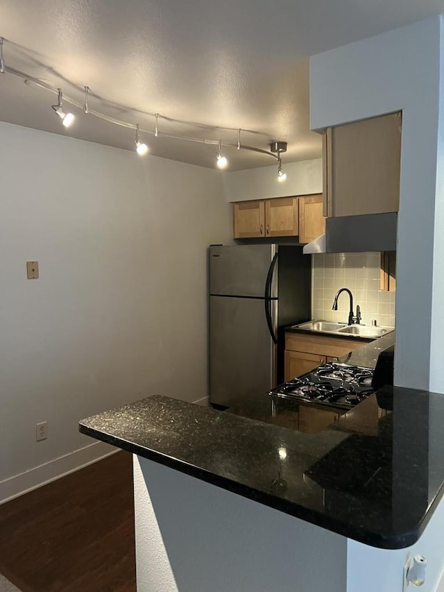 kitchen featuring range, tasteful backsplash, sink, kitchen peninsula, and stainless steel fridge