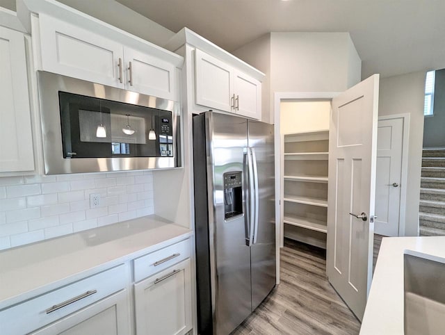 6839 Belle Fontaine Blvd, Middleton, WI 53562 - kitchen featuring stainless steel appliances, light wood-style flooring, white cabinets, light countertops, and tasteful backsplash