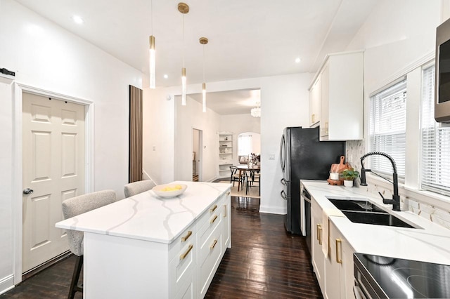 kitchen with electric stove, a breakfast bar, white cabinetry, hanging light fixtures, and a kitchen island