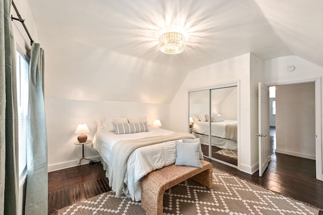 bedroom with dark wood-type flooring, lofted ceiling, and a closet