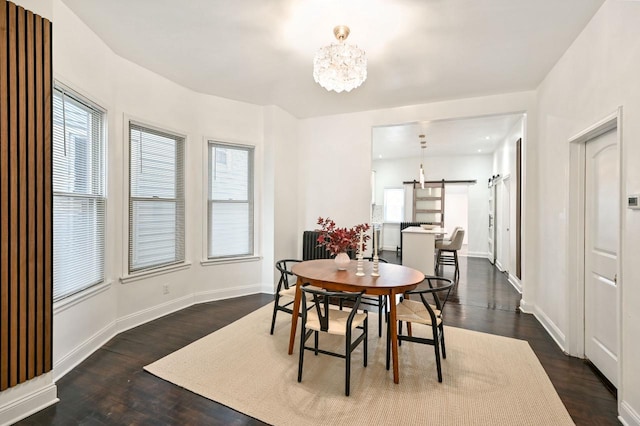 dining area with dark wood-type flooring, a barn door, and a chandelier