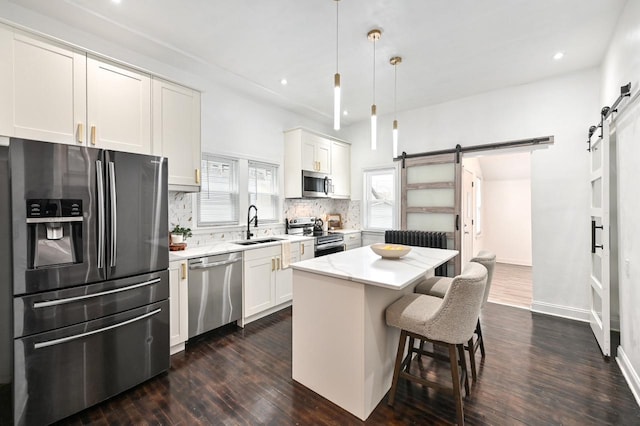 kitchen featuring pendant lighting, a kitchen island, a barn door, and appliances with stainless steel finishes