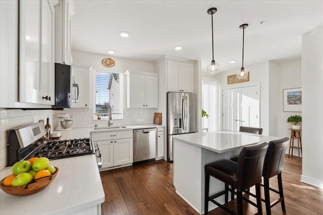 kitchen with a kitchen island, appliances with stainless steel finishes, sink, and white cabinets