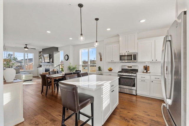 kitchen with a kitchen island, white cabinetry, appliances with stainless steel finishes, and hanging light fixtures