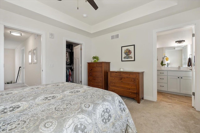 bedroom featuring ensuite bathroom, sink, a spacious closet, light carpet, and a closet