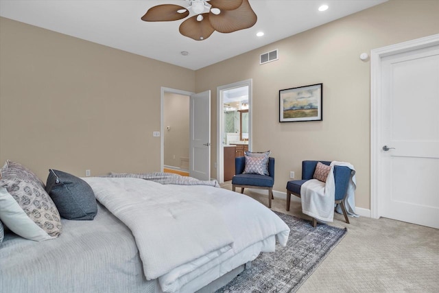 bedroom featuring ensuite bathroom, light carpet, and ceiling fan