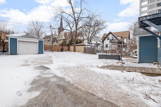 snowy yard with a garage and an outbuilding