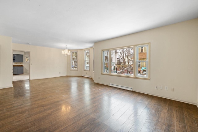 spare room featuring dark wood-type flooring, baseboard heating, and a chandelier