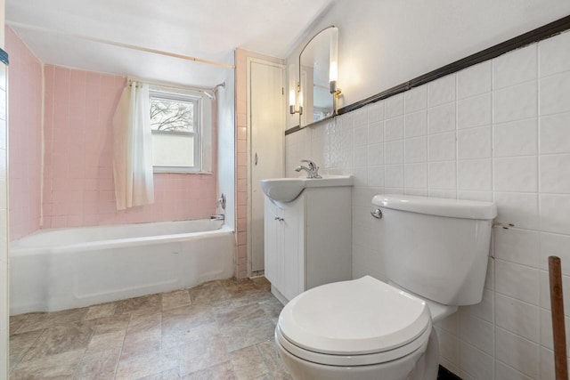 full bathroom with tile walls, toilet, vanity, and tiled shower / bath