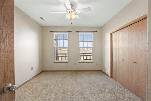 unfurnished bedroom with ceiling fan, light colored carpet, and a closet