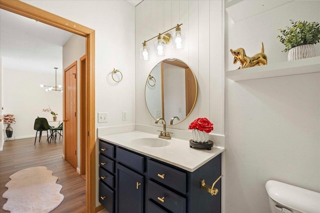 bathroom with hardwood / wood-style flooring, toilet, vanity, and an inviting chandelier