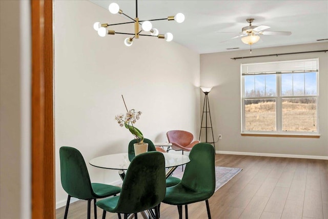 dining room with ceiling fan with notable chandelier and hardwood / wood-style floors