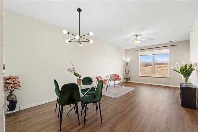 dining room with ceiling fan with notable chandelier and dark hardwood / wood-style floors