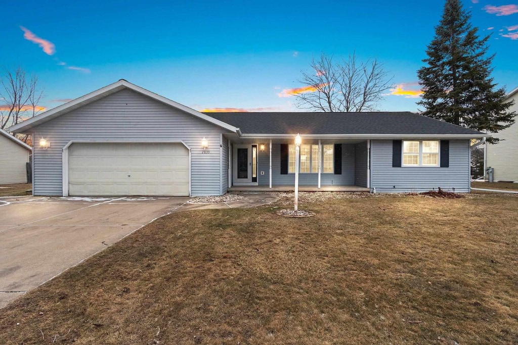 ranch-style house with covered porch, a yard, and a garage