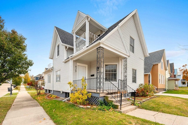 view of front of house featuring a balcony and a front lawn