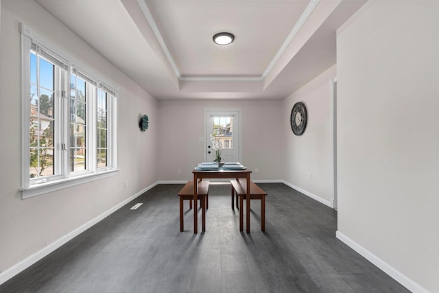 dining room featuring crown molding, dark wood-type flooring, and a raised ceiling