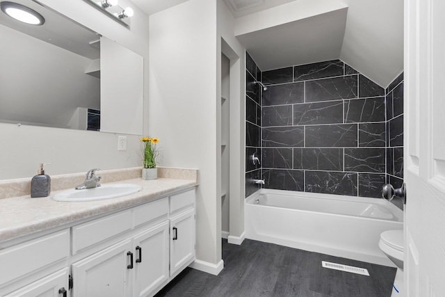 full bathroom with tiled shower / bath combo, lofted ceiling, vanity, toilet, and hardwood / wood-style flooring