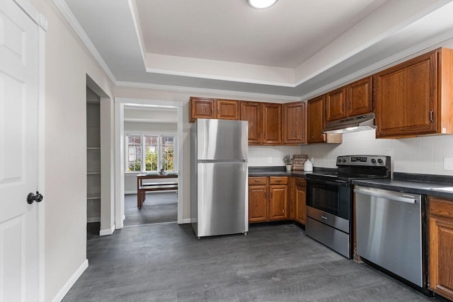 kitchen with backsplash, a raised ceiling, ornamental molding, and appliances with stainless steel finishes