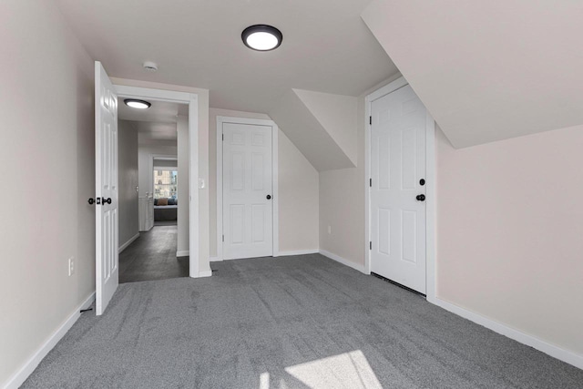 additional living space with dark carpet and vaulted ceiling