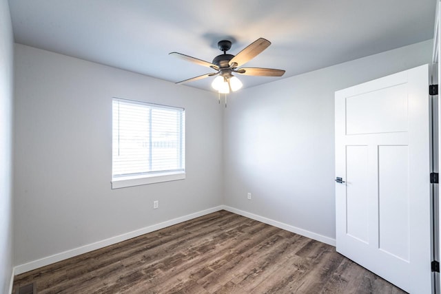 spare room with dark wood-type flooring and ceiling fan