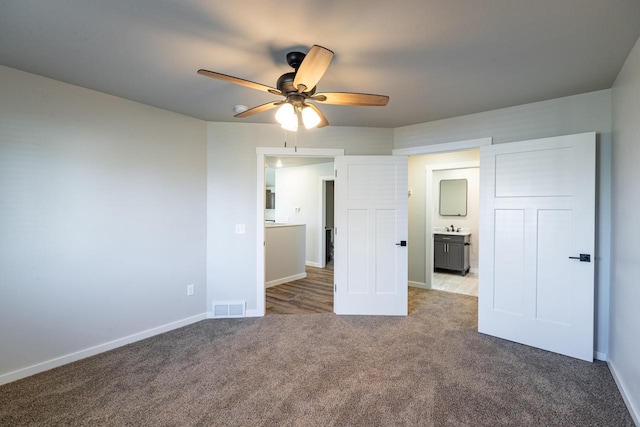 unfurnished bedroom featuring sink, ceiling fan, ensuite bathroom, and light carpet