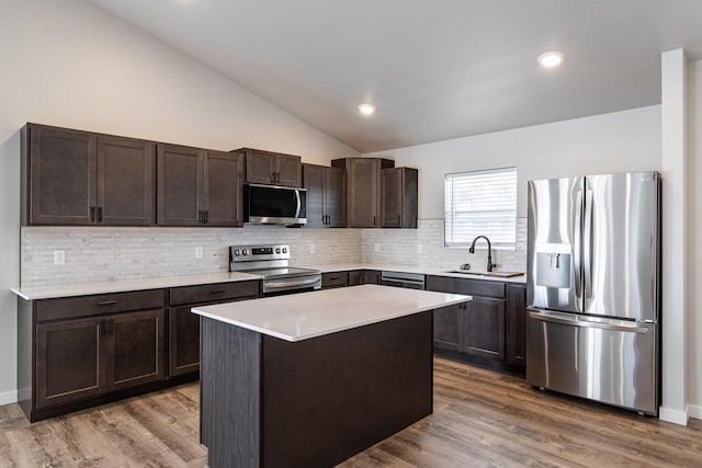 kitchen featuring hardwood / wood-style flooring, decorative backsplash, sink, a kitchen island, and stainless steel appliances