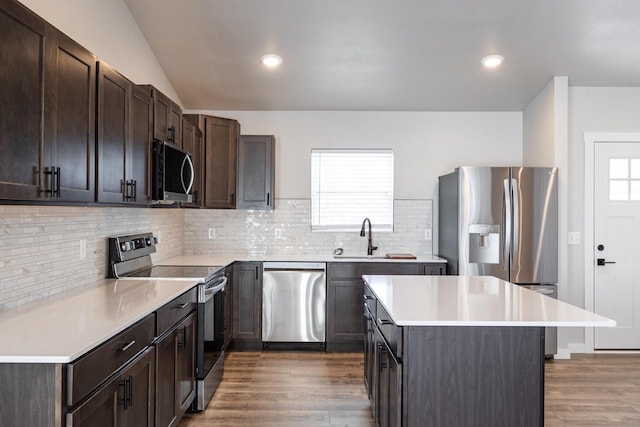 kitchen with sink, stainless steel appliances, a kitchen island, and dark brown cabinets