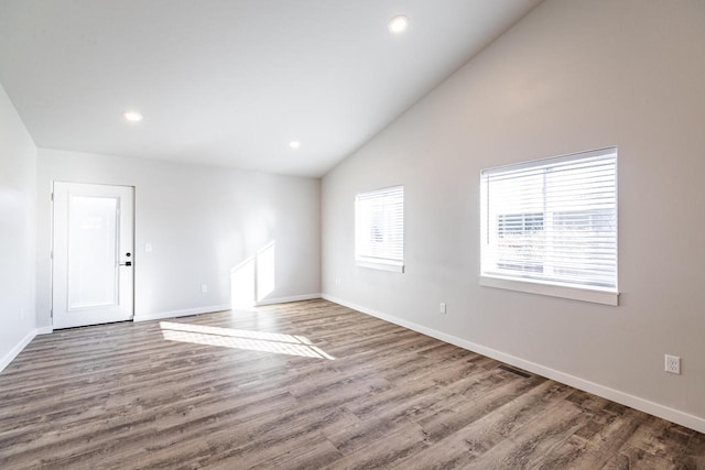 spare room featuring hardwood / wood-style floors and high vaulted ceiling