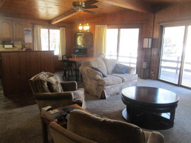 living room featuring vaulted ceiling with beams, wood ceiling, plenty of natural light, and wooden walls