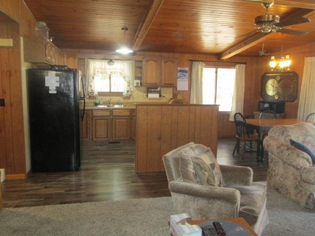 kitchen featuring black refrigerator, sink, beam ceiling, and dark wood-type flooring