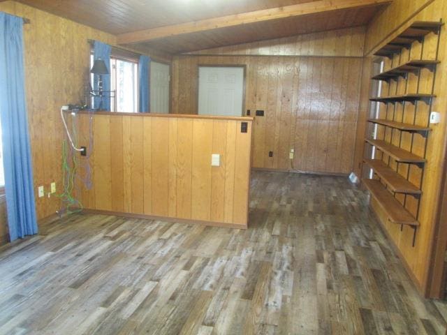 spare room featuring dark wood-type flooring, vaulted ceiling with beams, and wood walls