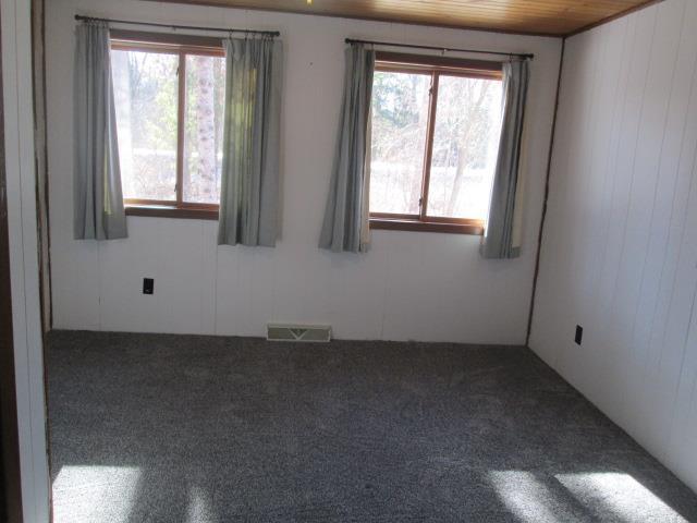 spare room featuring wood ceiling and wooden walls