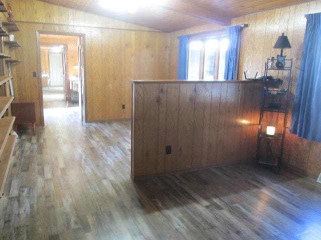 unfurnished room with lofted ceiling with beams, dark hardwood / wood-style floors, wood ceiling, and wooden walls