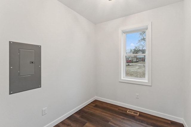 empty room with electric panel, dark hardwood / wood-style floors, and a healthy amount of sunlight