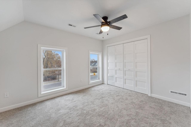 unfurnished bedroom with carpet floors, a closet, vaulted ceiling, and ceiling fan