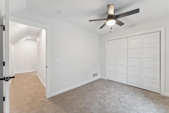 unfurnished bedroom featuring light colored carpet, a closet, vaulted ceiling, and ceiling fan