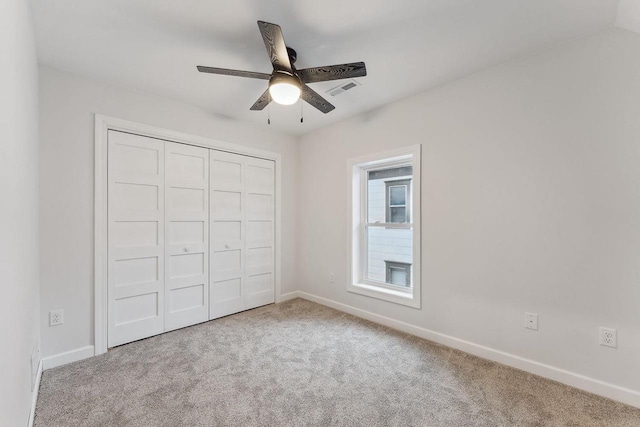 unfurnished bedroom featuring light colored carpet, a closet, and ceiling fan