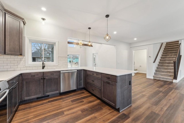 kitchen featuring pendant lighting, appliances with stainless steel finishes, dark brown cabinetry, tasteful backsplash, and kitchen peninsula