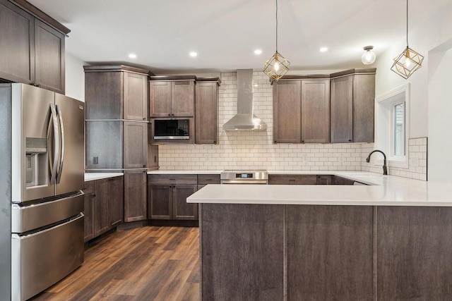 kitchen with pendant lighting, sink, backsplash, wall chimney range hood, and stainless steel appliances