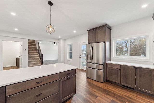 kitchen featuring dark hardwood / wood-style floors, stainless steel fridge, hanging light fixtures, and a wealth of natural light